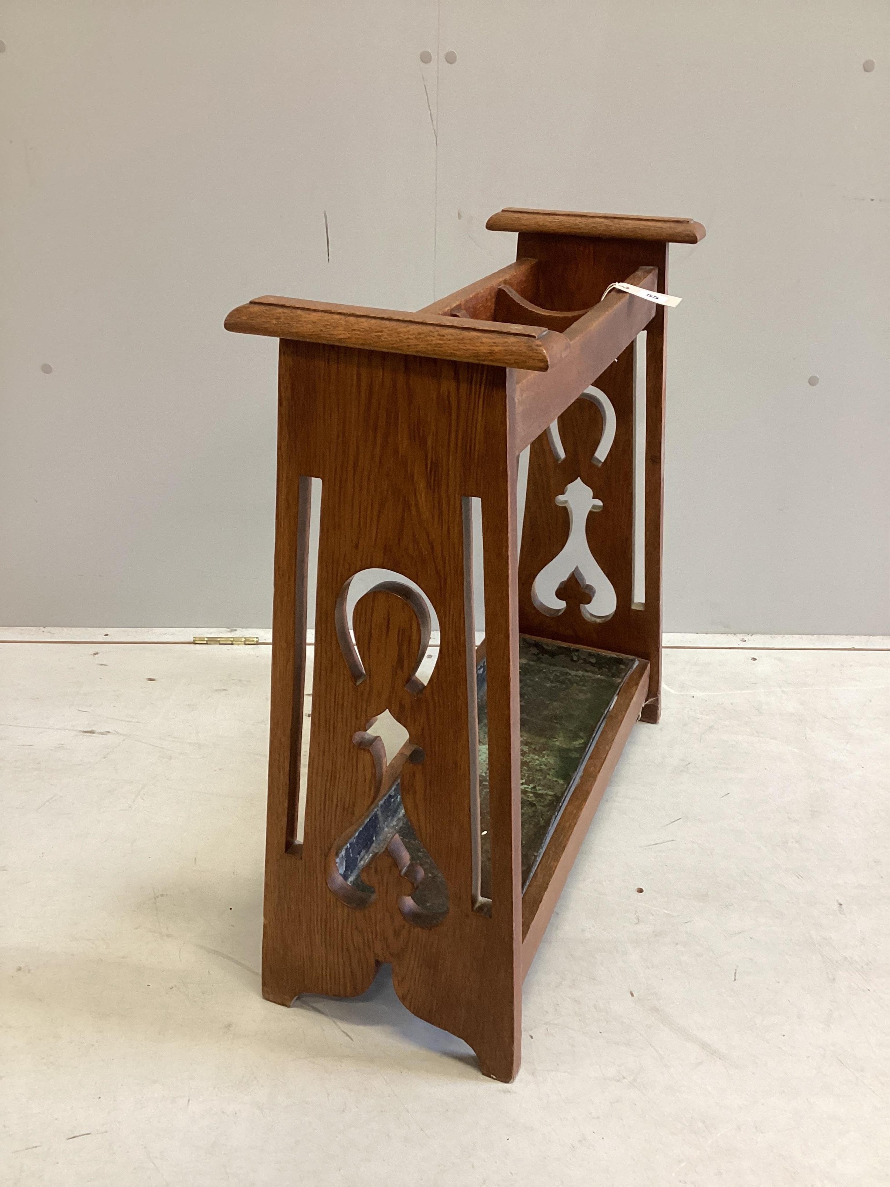 An Arts & Crafts oak four division stickstand, width 67cm, depth 26cm, height 73cm. Condition - good, drip tray misshapen and worn.